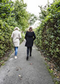 Twee vrouwen lopen samen over een smal pad tussen het groen