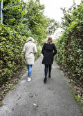 Twee vrouwen wandelen over een pad tussen de hagen
