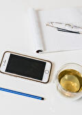 Notitieblok, telefoon, bril en een kop thee op tafel
