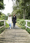 Twee vrouwen wandelen samen over een houten vlonderpad